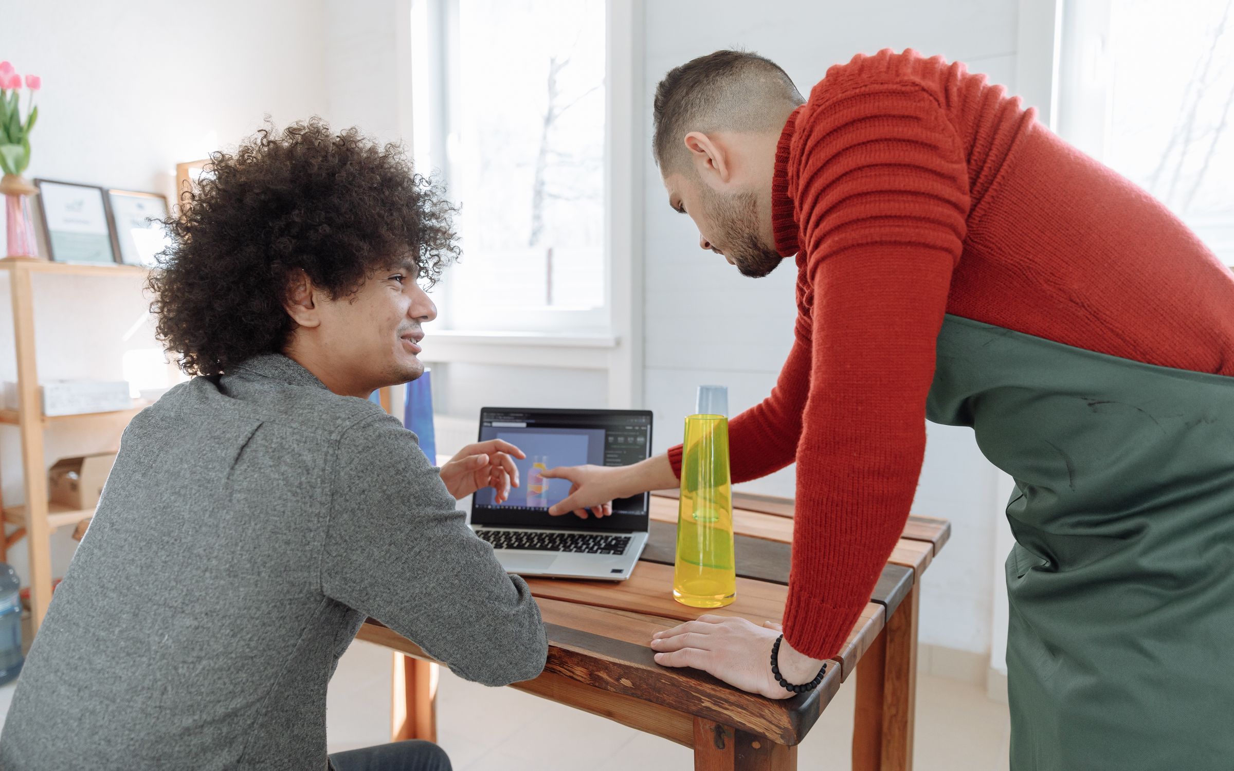 Two people discussing work on a laptop in a small business workspace